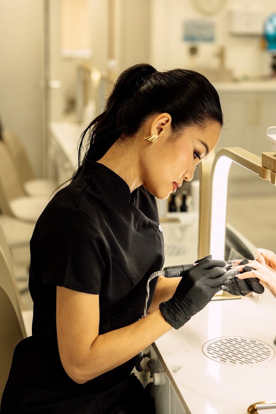 A nail technician using an e-file at the desk