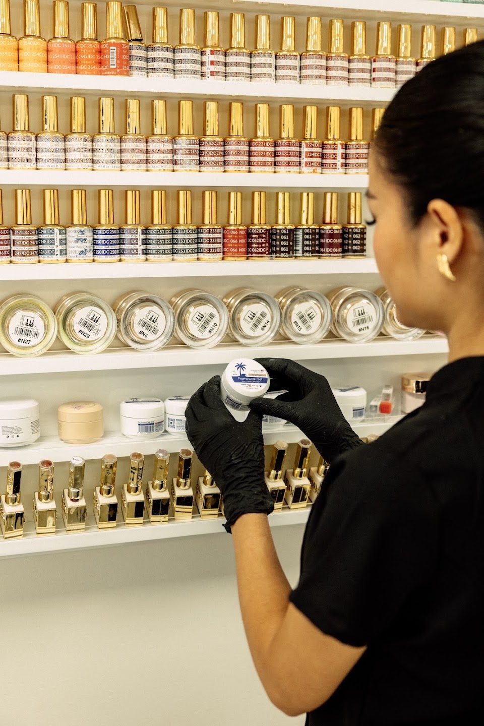 A nail technician choosing gel from the polish wall