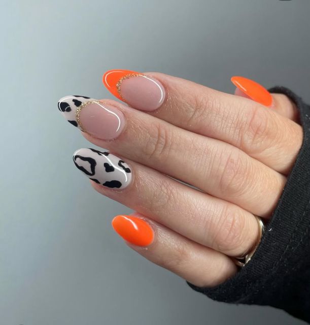 Bright orange French tip gel nails with cow print nail art