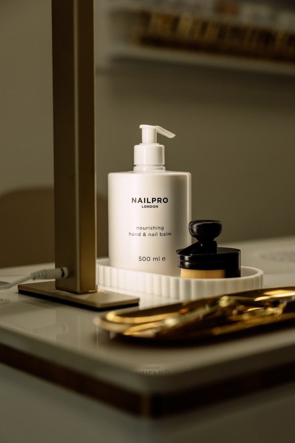 Hand cream and cuticle scissors on a salon shelf